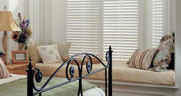 Plantation shutters in a modern bedroom bay window.